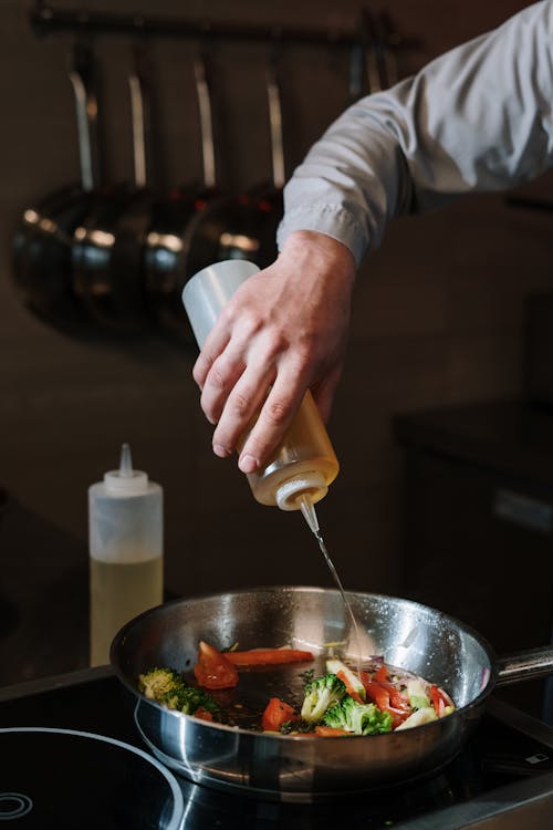 Pouring light smoked olive oil into a pan