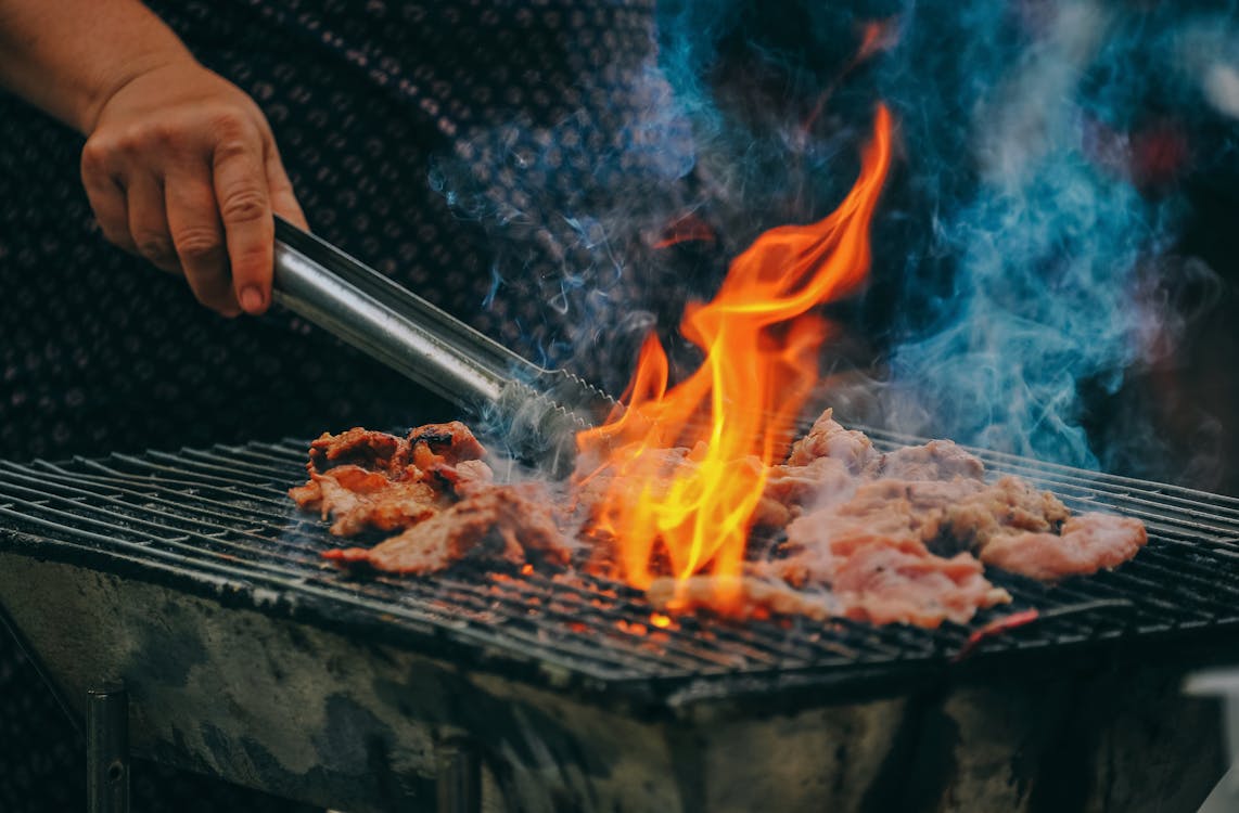 Close-up of a man cooking meat on a grill